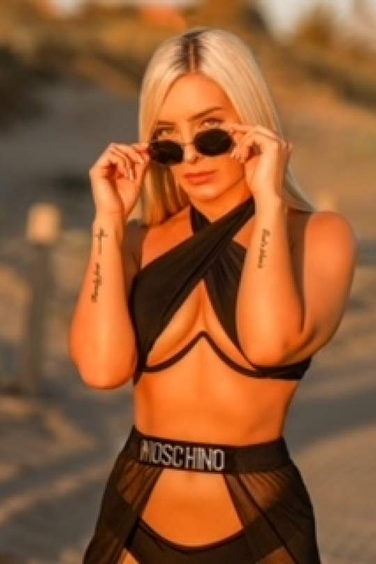 Michelle on a beach wearing a black bra